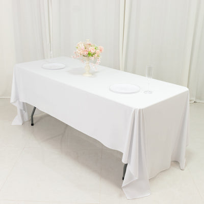 Dining table set for an elegant occasion with white tablecloth and floral centerpiece.