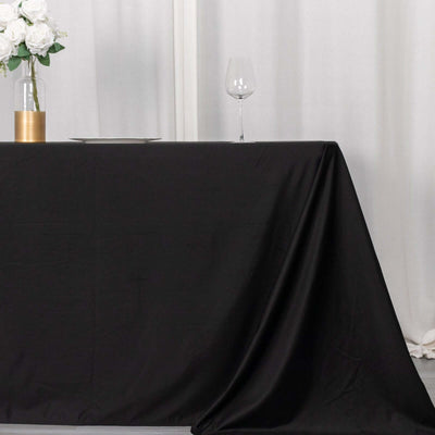 Black tablecloth draped elegantly over a table with a glass and flowers