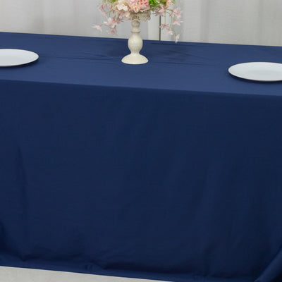 Navy tablecloth on a dining table with decorative vase and plates.