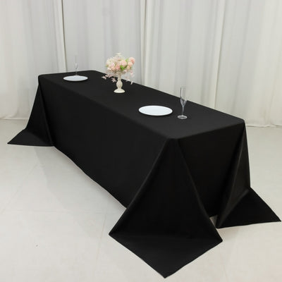 Black tablecloth on a dining table with plates and glasses.