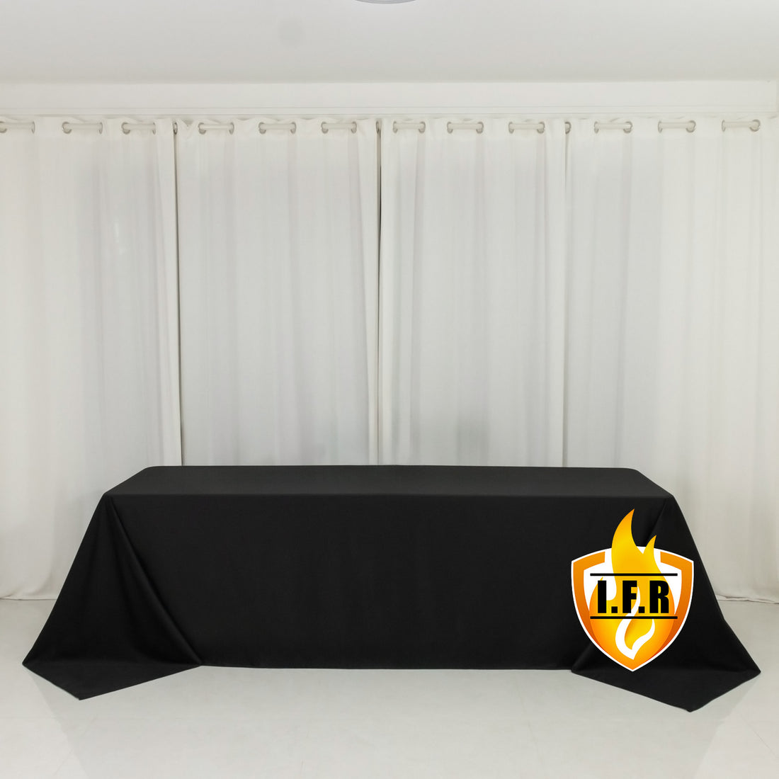 Black tablecloth on a table with white curtains in the background.