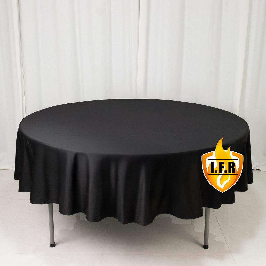 Black round tablecloth on display table with white curtain backdrop