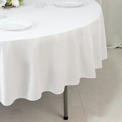 White tablecloth draped over a round table with empty plates and glassware.