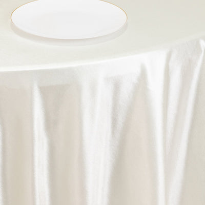 Elegant white tablecloth draping over a table with a simple white plate.