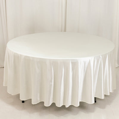 Round white tablecloth draped over a circular table in a studio setting.