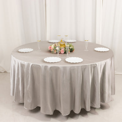 Elegant round table set with a beige tablecloth and decorative centerpiece.