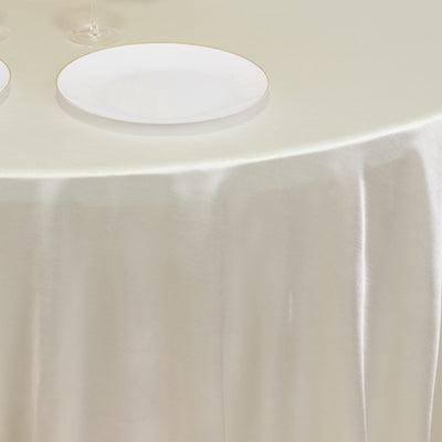 Elegant round table with a smooth satin tablecloth and white plates.