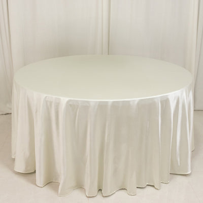 Round table with elegant satin tablecloth in soft cream color
