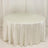 Round table with a white tablecloth in a studio setting.