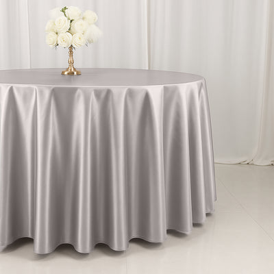 Elegant silver tablecloth draped over a round table with a floral centerpiece.