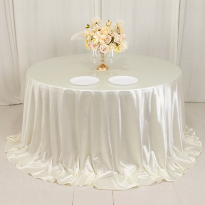 Elegant round table with satin cream tablecloth and floral centerpiece.
