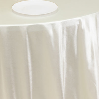 Elegant satin tablecloth draping over a table with a white plate on top.