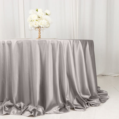 Elegant silver tablecloth draping over round table with floral centerpiece.