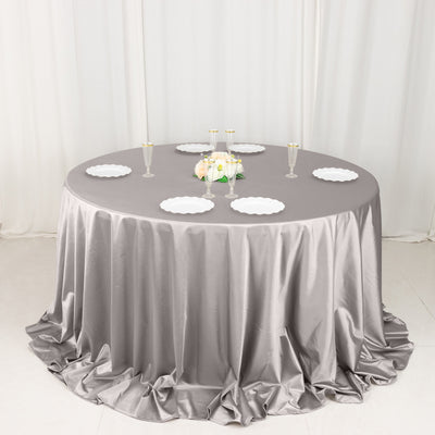 Round table with gray satin tablecloth and elegant table setting.