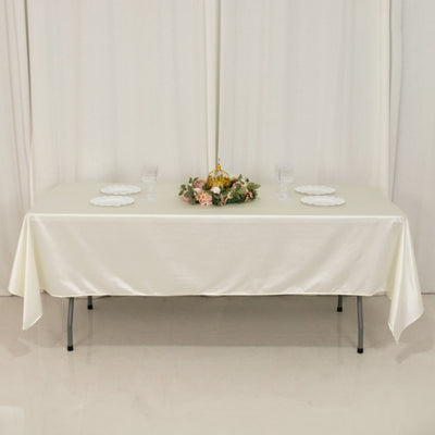 Elegant cream tablecloth draped over a table with decorative centerpiece and plates.
