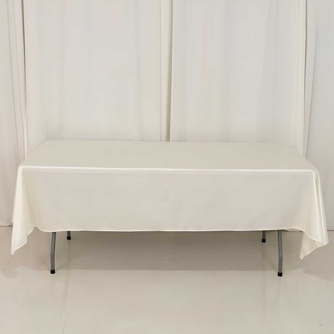White table covered with a smooth tablecloth in a studio setting.