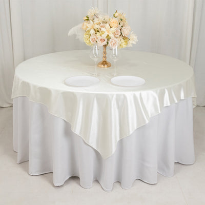 Elegant round table with satin white tablecloth and floral centerpiece.