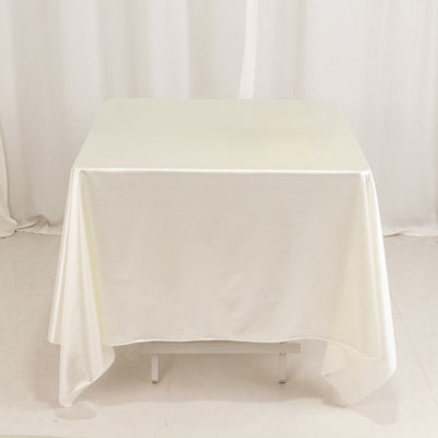 White tablecloth draped over a square table in a studio setting.