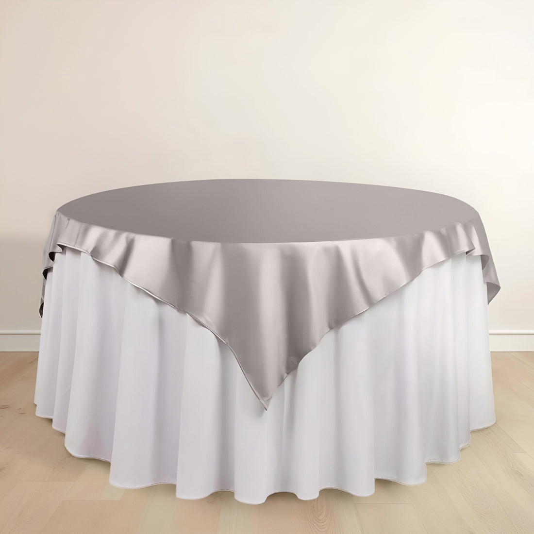 Round table with elegant gray satin overlay on white tablecloth
