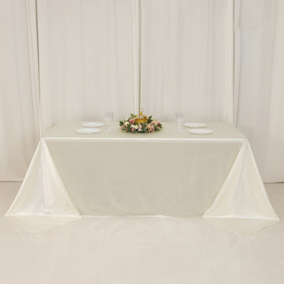 Elegant cream tablecloth draped over a table with floral centerpiece and plates.