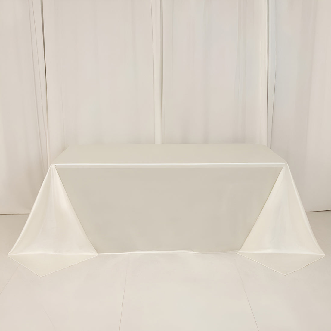 White table draped with a smooth fabric in a studio setting.