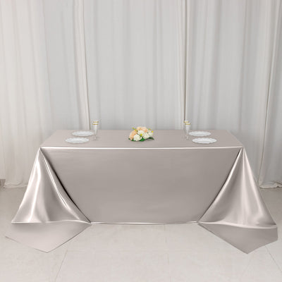 Elegant silver tablecloth draped over a table with floral centerpiece and plates.