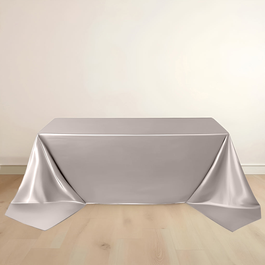 Silver tablecloth draped over a table on a light wooden floor.