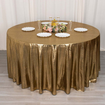 Gold tablecloth draped over a round table, styled with plates and floral centerpiece.