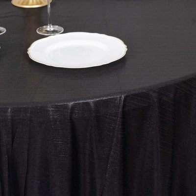 Elegant black tablecloth draped over a round table with a white plate and glassware.