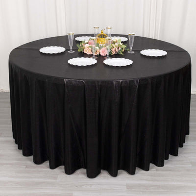 Round black tablecloth with elegant table setting and floral centerpiece.