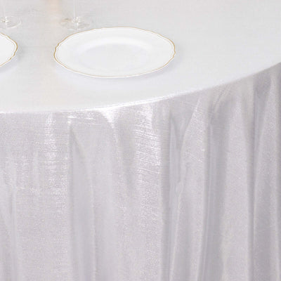 Elegant silver tablecloth draped over a round table with plates and glasses.