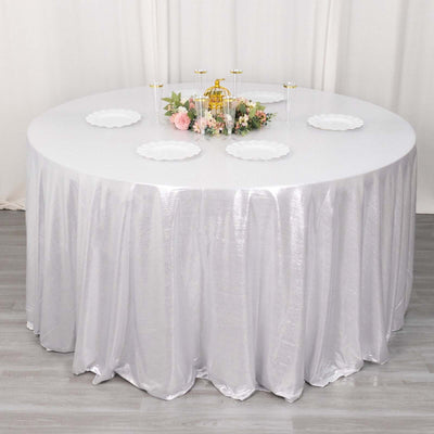 Round table with a shiny silver tablecloth and decorative centerpiece.