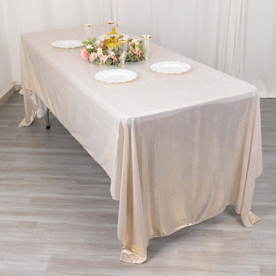 Elegant table setup with a shimmering beige tablecloth and decorative centerpiece.