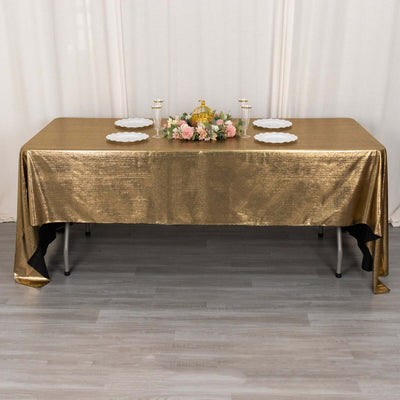 Gold tablecloth draped over a table with plates and floral centerpiece.