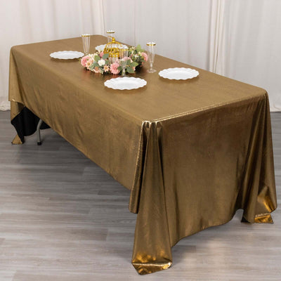 Elegant gold tablecloth draped over a table with decorative plates and flowers.
