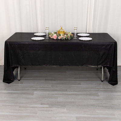 Black tablecloth draped over a table set with plates and decorative centerpiece.