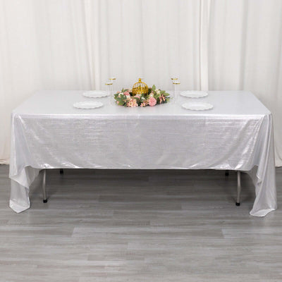 Elegant silver tablecloth draped over a table with floral centerpiece and plates.