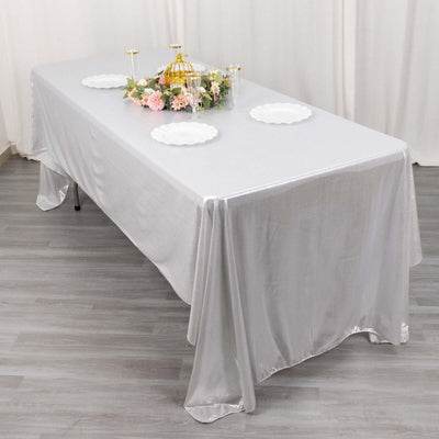 Silver tablecloth draped over a table set with decorative plates and flowers.