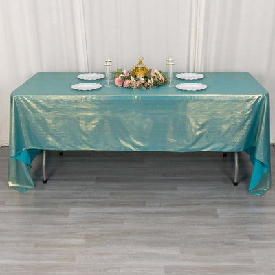 Turquoise tablecloth draped over a table with plates and floral centerpiece.