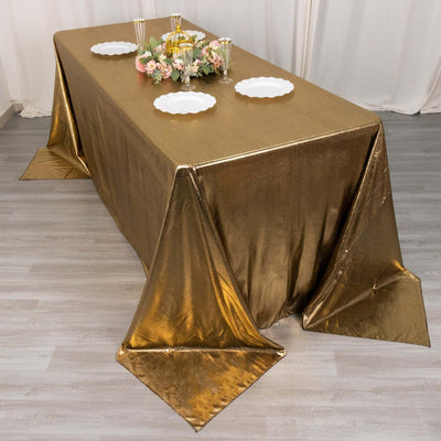 Gold tablecloth draped over a table with decorative plates and flowers.