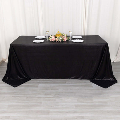 Black tablecloth draped over a table with floral centerpiece and plates.