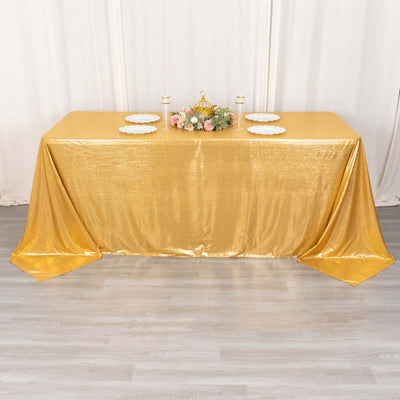 Gold tablecloth draped over a table with decorative plates and floral centerpiece.