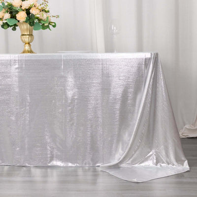 Silver tablecloth draped elegantly on a table with floral centerpiece and wine glass.