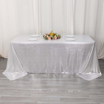 Silver tablecloth draped elegantly over a table with floral centerpiece and plates.