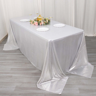 Silver tablecloth draped elegantly over a table with decorative plates and flowers.