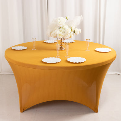 Round table set with white plates and floral centerpiece on a golden tablecloth.