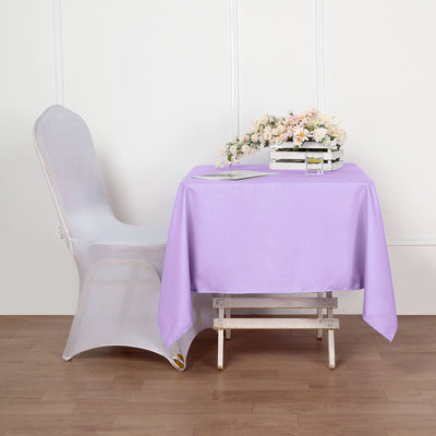Lavender tablecloth draped over a wooden table with flowers and a chair