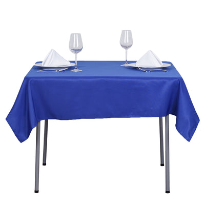 Blue tablecloth set with glasses and plates on a dining table.