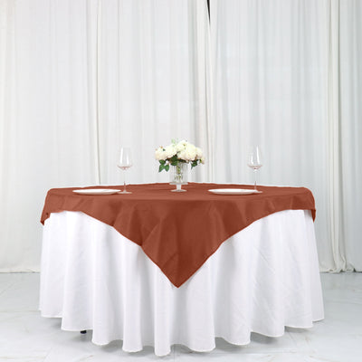 Brown tablecloth draped over a round table with wine glasses and floral centerpiece.