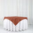 Brown tablecloth draped over a white table in a studio setting.
